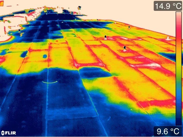 Infrared thermal image of a flat roof showing a patchwork of warm and cool areas across the insulation boards